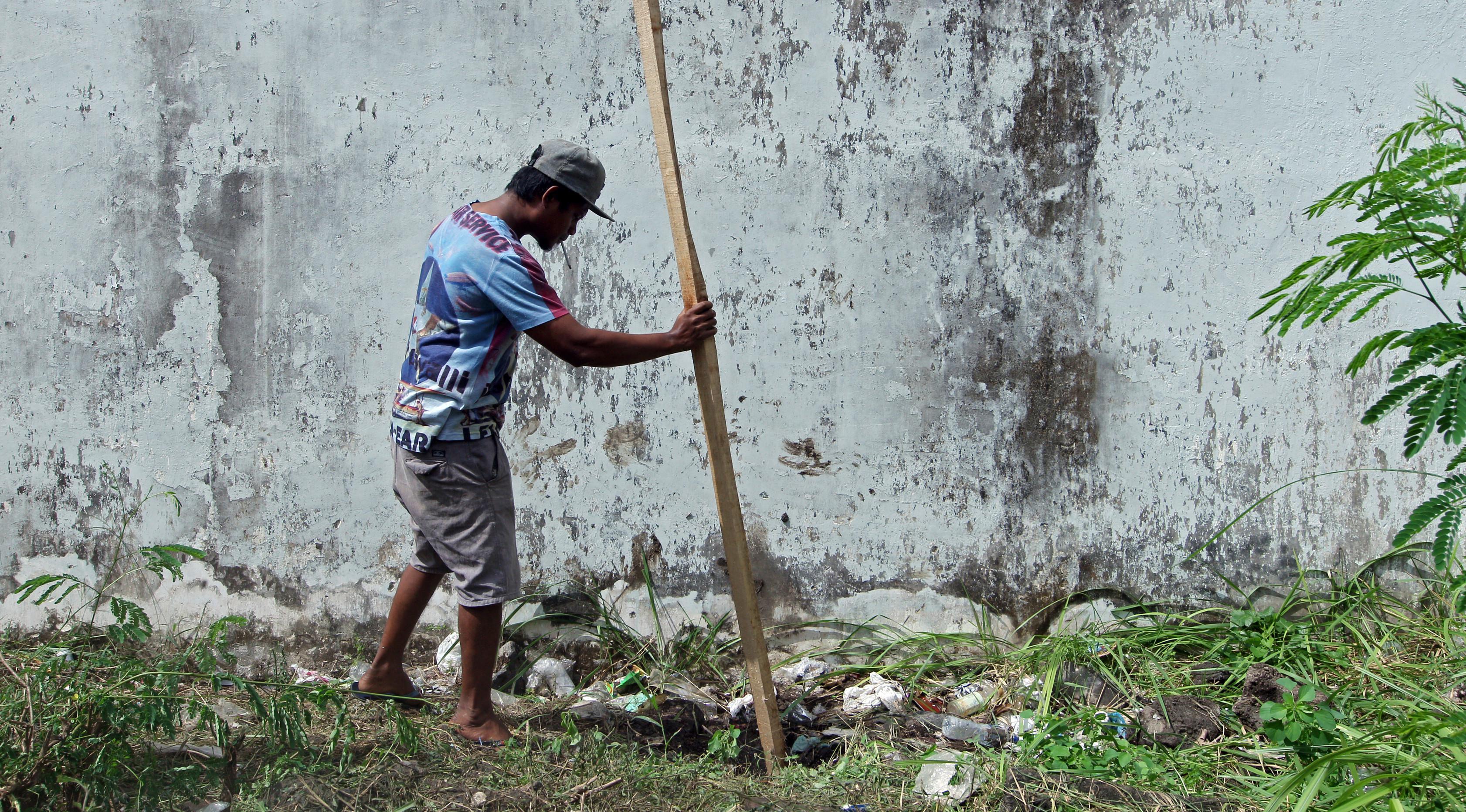 Seorang pria memasukkan kayu ke dalam lubang yang digunakan narapidana untuk kabur dari Lapas Kerobokan, Bali, Senin (19/6). Empat narapidana asing kabur melalui lubang sepanjang 15 m yang mengarah ke parit di luar bangunan Lapas. (AP /Firdia Lisnawati)