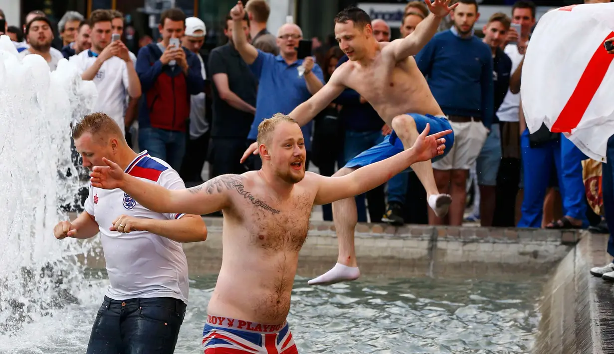 Sejumlah suporter Inggris masuk ke kolam air mancur yang berada di tengah Kota Lille, Prancis (16/6). Aksi ini mereka lakukan setelah mengatahui Timnas Inggris berhasil mengalahkan Wales dalam pertandingan piala Eropa 2016. (REUTERS / Wolfgang Rattay)