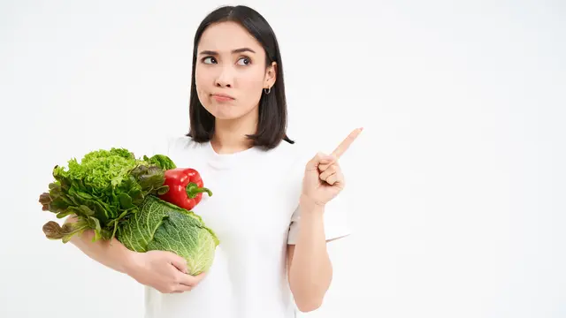 Seorang perempuan sedang memegang sayur-sayuran di lengannya (Foto Dok: Freepik/benzoix)