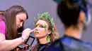 Seorang makeup artist merias model saat mengikuti kompetisi makeup di International "Crystal Angel" Festival of Hairdressing ke-15 di Kiev (22/4). (AFP/Sergei Supinsky)