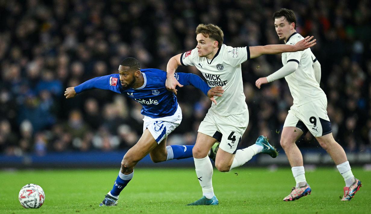 Pemain Everton, Beto (kiri) berebut bola dengan pemain Peterborough, Archie Collins pada laga putaran ketiga Piala FA 2024/2025 di Goodison Park, Liverpool, Inggris, Jumat (10/01/2025) WIB. (AFP/Oli Scarff)