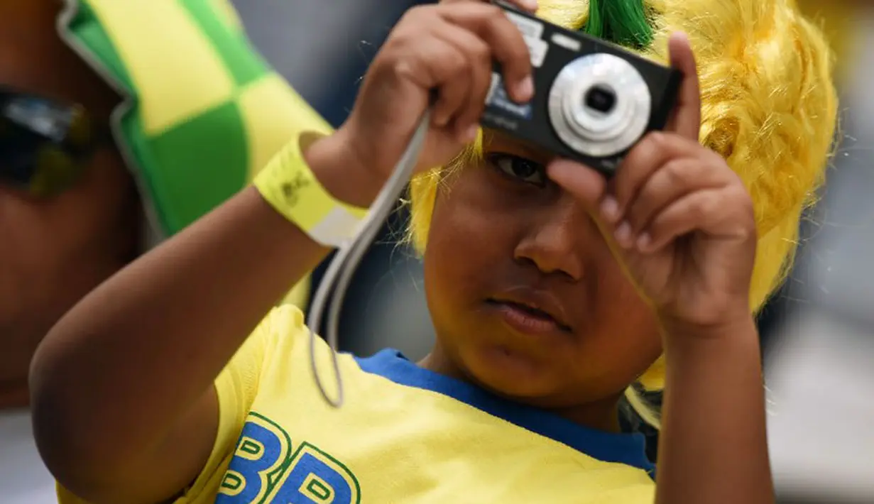 Bergaya bak fotografer profesional, seorang bocah Brasil mengabadikan laga Iran kontra Nigeria di babak penyisihan Piala Dunia 2014 Grup F di Baixada Arena, 16/6/2014). (AFP PHOTO/Jewel Samad)