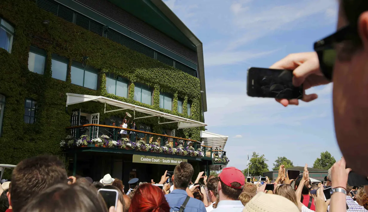 Serena Williams memamerkan trofi Wimbledon kepada para penggemar dari balkon Center Court. (REUTERS/Stefan Wermuth)