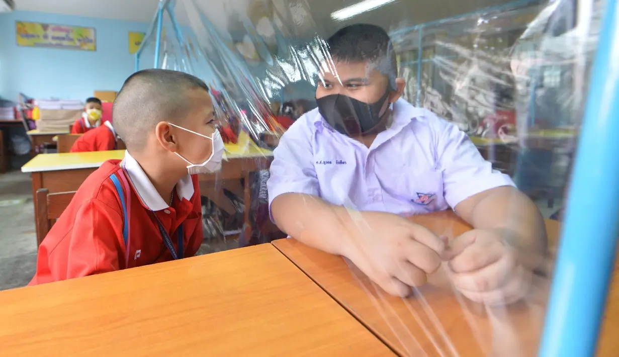 Para siswa saling mengobrol dengan dibatasi lembaran plastik di sebuah sekolah di Bangkok, Thailand (1/7/2020). Sekolah-sekolah di Thailand telah dibuka kembali pada Rabu (1/7). (Xinhua/Rachen Sageamsak)