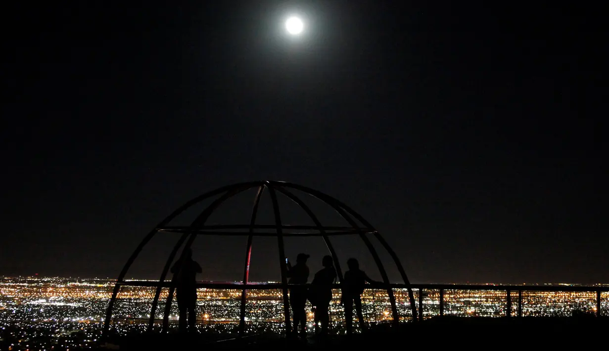 Sejumlah orang berfoto sambil menyaksikan fenomena Supermoon dari sebuah dataran tinggi di Ciudad Juarez, Meksiko, Minggu (16/10). Fenomena ini terjadi setiap tahun ketika orbit bulan berada berada dekat dengan bumi. (Reuters/Jose Luis Gonzalez)