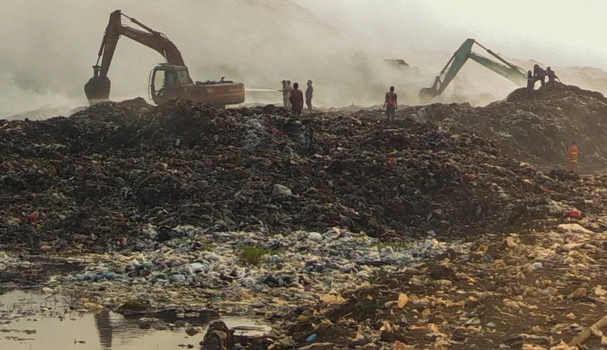 Petugas pemadam kebakaran dan alat berat  berusaha memadamkan api di Tempat Pembuangan Akhir (TPA) Jatiwaringin, Kabupaten Tangerang, Banten, Jumat (03/07/2026). (Merdeka.com/ Arie Basuki)