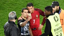 Seorang penggemar masuk lapangan dan mengajak berfoto Cristiano Ronaldo seusai laga Portugal melawan Austria pada laga kedua Grup F Piala Eropa 2016di Parc des Princes, Minggu (19/6/2016) dini hari WIB. (AFP/Miguel Medina)