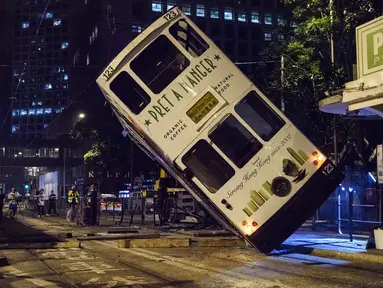 Sebuah trem double-decker diangkat menggunakan crane setelah terbalik di jalan utama di Hong Kong, Kamis (6/4). Kecelakaan yang terjadi tengah malam waktu setempat itu mengakibatkan 11 orang mengalami luka-luka. (ANTHONY WALLACE / AFP)
