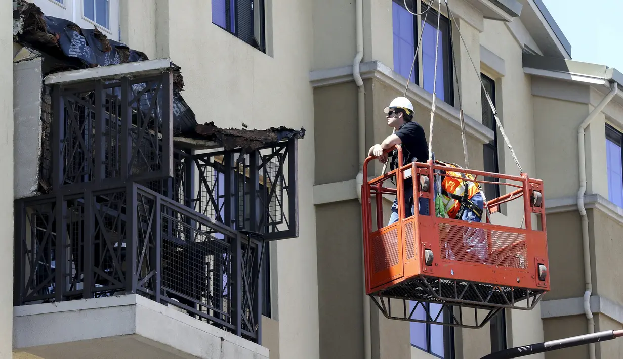 Pekerja memeriksa kerusakan balkon di lantai 4 dari sebuah apartemen yang runtuh, di California, AS, 16 Juni 2015. Enam orang mahasiswa yang berada di balkon itu dikabarkan terjatuh dan tewas. (REUTERS/Elia Nouvelage)