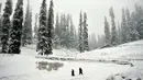 Pejalan kaki melintasi jalan yang tertutup salju di Gulmarg, sekitar 55 km sebelah utara Srinagar, Kashmir, Selasa (3/1). Gelombang dingin yang melanda Kashmir kian parah hingga mencapai suhu di bawah nol derajat celcius. (Tauseef Mustafa/AFP)