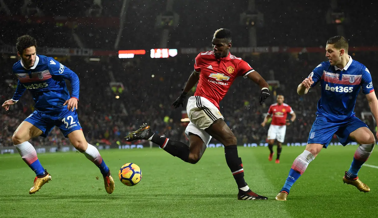 Gelandang Manchester United Paul Pogba berebut bola dengan pemain Stoke City, Ramadan Sobhi dan Kevin Wimmer pada laga pekan ke-23 Premier League 2017-2018 di Old Trafford, Senin (15/1). Manchester United melibas Stoke City 3-0. (Oli SCARFF/AFP)