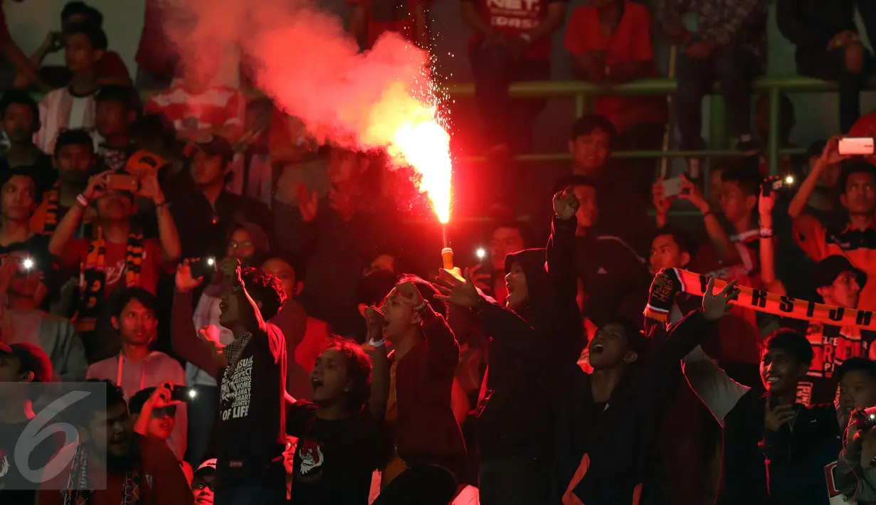 Suporter menyalakan suar usai menyaksikan laga Persija melawan Timnas Indonesia U-22 di Stadion Patriot Candrabhaga, Bekasi, Rabu (5/4). Laga Persija melawan Timnas Indonesia U-22 berakhir imbang 0-0. (Liputan6.com/Helmi Fithriansyah)