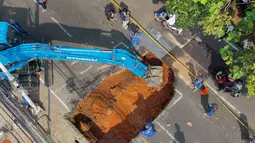 Foto udara menunjukkan aktivitas para pekerja menggunakan alat berat untuk membersihkan puing-puing dari lubang runtuhan yang terbentuk di Jalan Raya Lenteng Agung (arah Depok), Jakarta pada Jumat 29 Mei 2026. (BAY ISMOYO/AFP)
