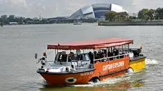 Sebuah wahana amfibi yang membawa turis melewati Stadion Nasional di Singapura pada 19 Februari 2019. Mobil-perahu mirip bebek ini mengantarkan pelancong berpetualang seru melihat keindahan Negeri Singa melalui jalur darat dan sungai. (Roslan RAHMAN/AFP)