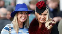 Senyum manis dua wanita cantik saat difoto jelang pembukaan ajang Pacuan Kuda dalam Festival Cheltenham di Inggris (16/3). Para wanita yang menghadiri pacuan kuda ini terkenal dengan gaya modisnya dan topi fancy yang dikenakannya. (REUTERS/Paul Childs)