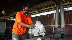 Pekerja memasukkan kantong plastik ke dalam mesin pengolah untuk memproduksi Petasol dalam sebuah lokakarya di Pekanbaru, Riau, pada 8 Agustus 2025. (Wahyudi/AFP)