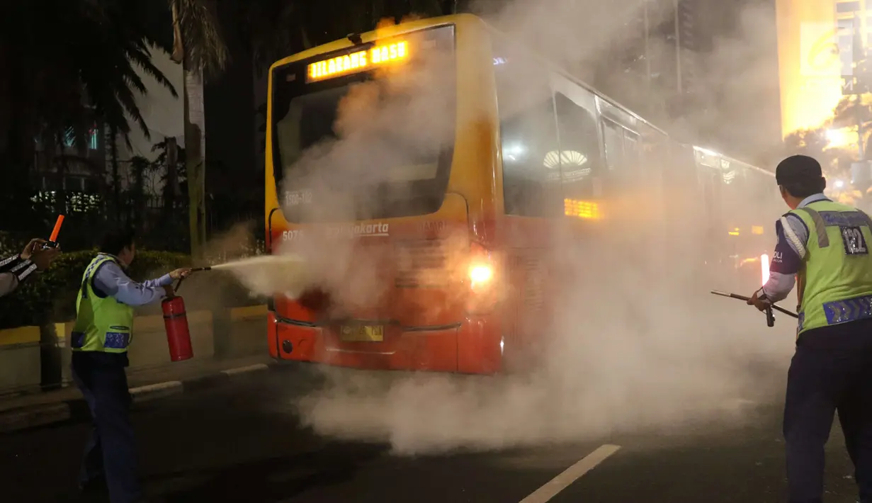 Petugas menyemprotkan apar ke TransJakarta yang mengeluarkan asap dari dalam mobil di Bundaran HI, Jakarta, Rabu (25/4) malam. TransJakarta koridor 1 tersebut mengeluarkan asap usai terdengar suara ledakan. (Liputan6.com/Angga Yuniar)
