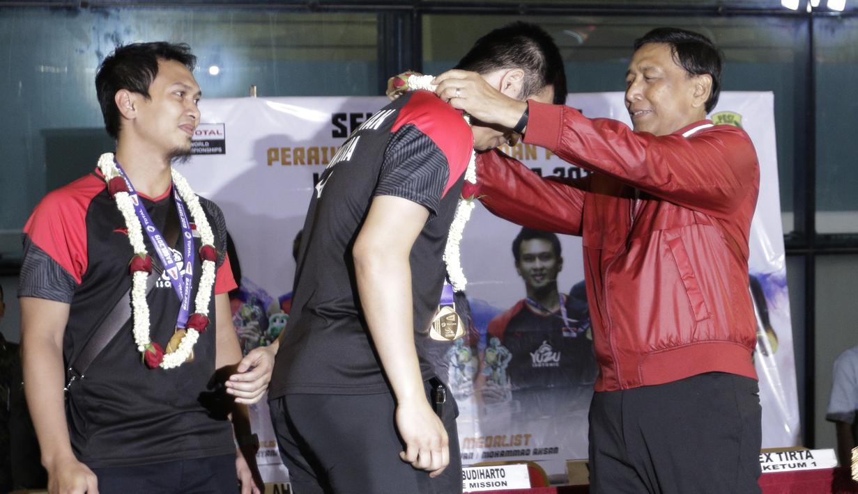 Ketum PP PBSI, Wiranto, mengalungkan bunga kepada pasangan ganda putra Indonesia, Mohammad Ahsan/Hendra Setiawan, di Bandara Soekarno-Hatta, Tangerang, Selasa (27/8). Ahsan/Hendra meraih gelar pada Kejuaraan Dunia Bulutangkis 2019. (Bola.com/Yoppy Renato)