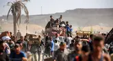 Orang-orang berjalan membawa paket bantuan kemanusiaan yang mereka terima dari pusat distribusi yang dikelola oleh Yayasan Kemanusiaan Gaza (GHF) yang didukung Amerika Serikat (AS) dan Israel, di koridor Netzarim, Nuseirat, Jalur Gaza tengah, pada 30 September 2025. (Eyad BABA/AFP)