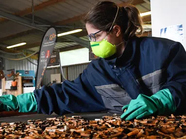 Pegawai Estelle Chabard menyortir puntung rokok di antara limbah di pabrik MeGo di Bourg-Blanc, Perancis (29/5). Perusahaan MeGo ini mengolah limbah puntung rokok menjadi barang praktis sehari-hari seperti bangku jalanan. (AFP/Fred Tanneau)
