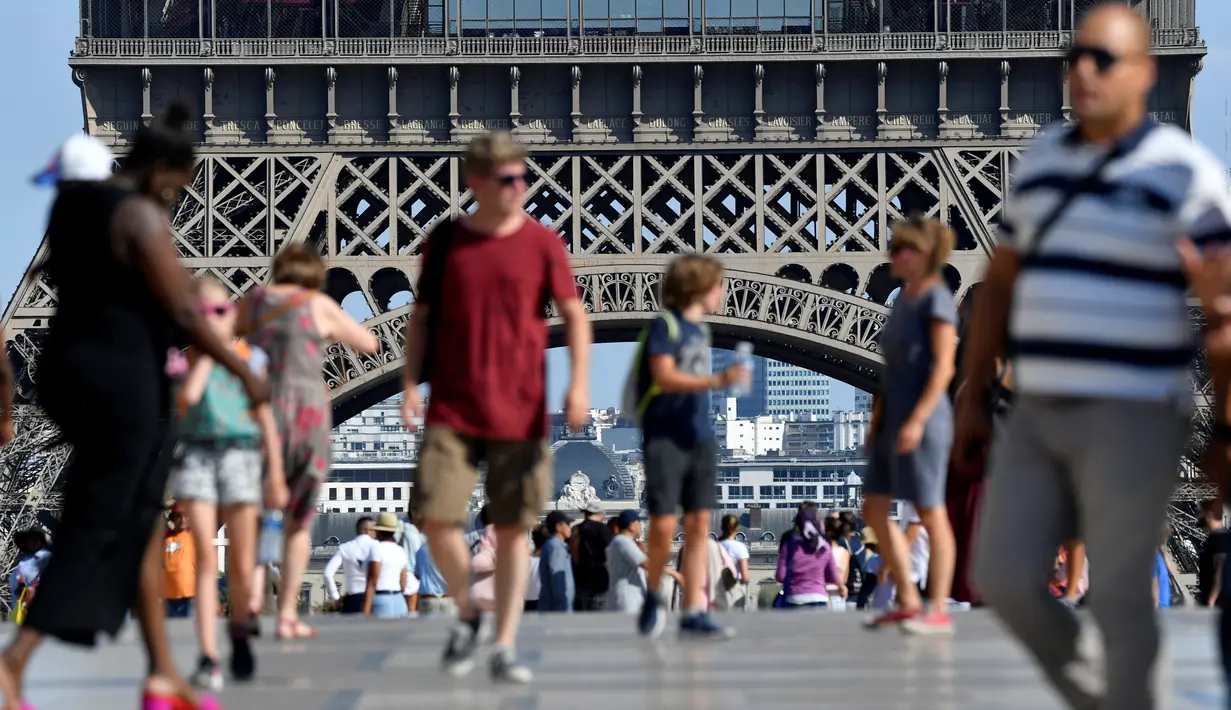 Turis berjalan di depan Menara Eiffel, Paris, Kamis (2/8). Dua hari terakhir atau sejak Rabu (1/8), karyawan menara yang menjulang setinggi 324 meter ini mogok. (AFP PHOTO/GERARD JULIEN)