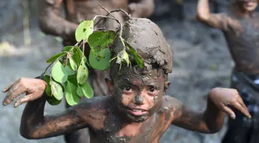 Seorang bocah berpose saat tradisi mandi lumpur atau mebuug-buugan di Desa Kedonganan, Denpasar, Bali, Jumat (8/3). Tradisi ini diadakan sehari setelah Hari Raya Nyepi. (Sonny Tumbelaka/AFP)