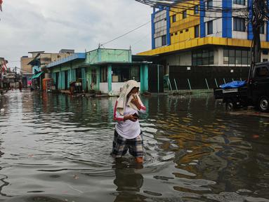 Warga melintasi banjir rob yang terjadi di kawasan Muara Baru, Jakarta Utara, Selasa (14/1/2025). (Liputan6.com/Angga Yuniar)