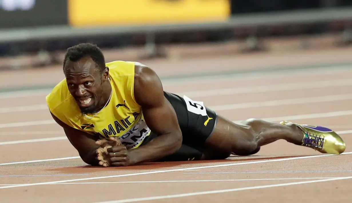 Pelari asal Jamaika, Usain Bolt terkapar di lintasan setelah terjatuh dan cedera di final 4x100 meter pada Kejuaraan Dunia Atletik di London, Sabtu (12/8). Bolt sempat tertatih-tatih sebelum akhirnya jatuh dan gagal melanjutkan lomba. (AP/Tim Ireland)