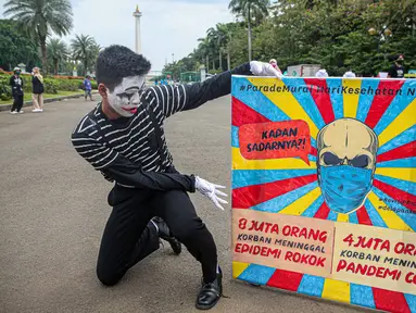 Seorang yang tergabung dalam Koalisi Masyarakat Peduli Kesehatan (KOMPAK) menunjukkan poster saat menggelar aksi #ParadeMural di kawasan Patung Arjuna Wijaya, Jakarta, Rabu (17/11/2021). Aksi tersebut untuk mendesak Presiden untuk mengesahkan Revisi PP 109/2012. (Liputan6.com/Faizal Fanani)
