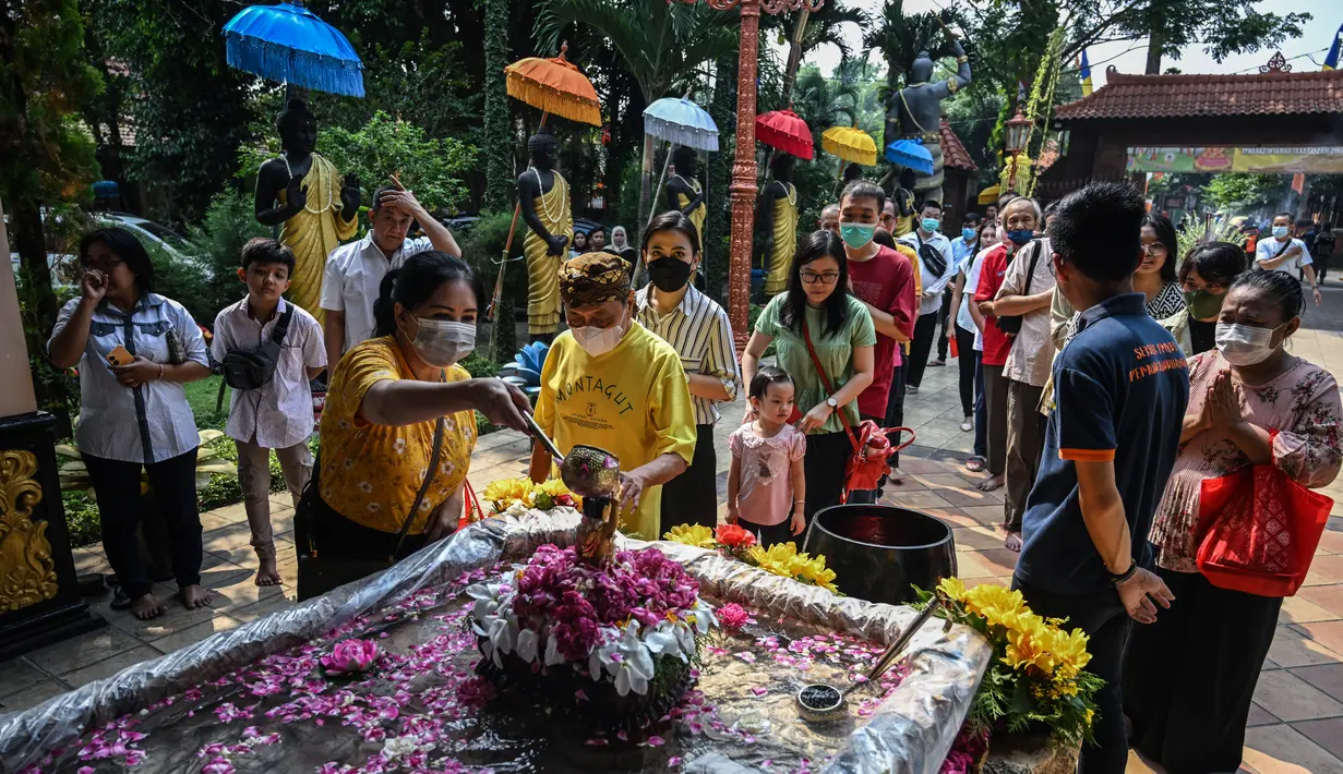 Umat Buddha menuangkan air suci di atas patung bayi Pangeran Siddhartha Gautama di Vihara Maha Vihara Mojopahit di Mojokerto pada 4 Juni 2023, saat umat Buddha merayakan hari Waisak. (AFP/Bagus Saragih)