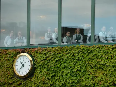 Staff restoran menyaksikan aksi pemain Serbia, Novak Djokovic saat berlatih sebelum melawan pemain Inggris Raya,  James Ward  pada Tenis Wimbledon Championships 2016 di The All England Lawn Tennis Club, Wimbledon,  London, (27/6/2016). (AFP/ Glyn Kirk)