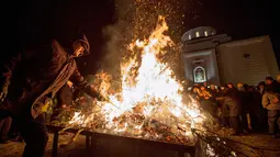 Seorang pria membakar ranting pohon oak kering  atau Yule log selama perayaan Hari Natal Ortodoks di Belgrade, Serbia (6/1). Umat Kristen Ortodoks di Serbia memiliki tradisi yang cukup unik dalam merayakan Natal, yaitu membakar ranting. (AFP/Oliver Bunic)