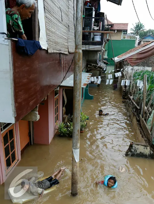 Anak-anak gang H. Maliki, Cawang memanfaatkan banjir untuk berenang, Jakarta, Senin (16/11). Pasca datangnya air kiriman dari Bogor, puluhan rumah di pinggir kali Ciliwung terendam banjir dengan ketinggian mencapai 3 meter. (Liputan6.com/Yoppy Renato)