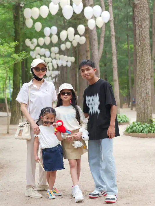Kebersamaan Sarwendah dengan keluarganya di Korea Selatan. Ia mengenakan kemeja lengan pendek berwarna putih, celana panjang cokelat, topi putih, sunglasses, dan rahang yang masih digips hitam. [Foto: Instagram/sarwendah29]