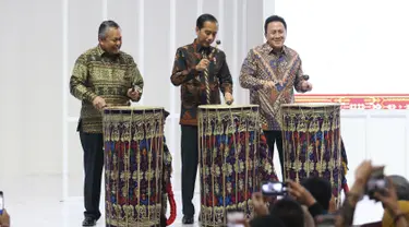 Presiden Joko Widodo (tengah) didampingi Gubernur Bank Indonesia Perry Warjiyo dan Kepala Bekraf Triawan Munaf (kiri) memukul gendang Beleq sebagai tanda peresmian pembukaan pameran Karya Kreatif Indonesia (KKI) 2019 di JCC Senayan, Jumat (12/7/2019). (Liputan6.com/Angga Yuniar)