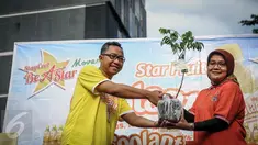 Perwakilan Coolant, Dwianto Arif (kiri) memberikan bibit blimbing kepada Erni Fitratunissa selaku Kepala Bidang Pelestarian & Tata Lingkungan BPLHD kegiatan Coolant Star Fruit di arena Car Free Day, Jakarta, Minggu (25/9). (Liputan6.com/Faizal Fanani)