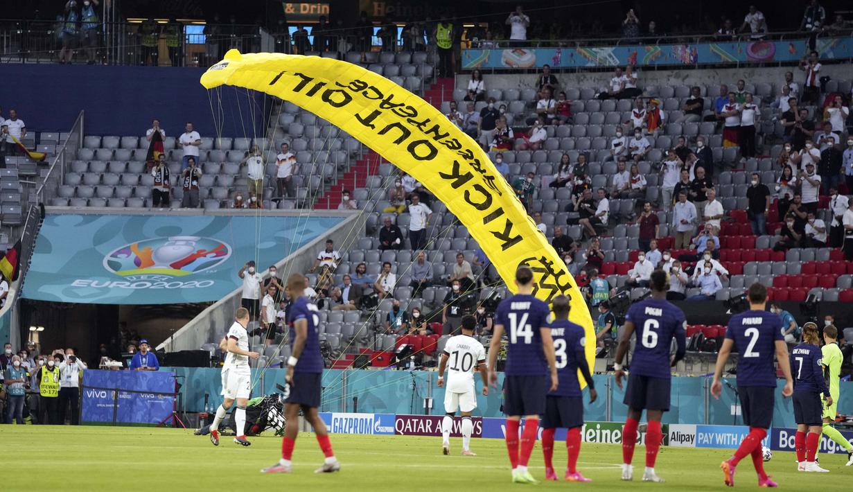 Seorang aktivis LSM lingkungan hidup Greenpeace tiba-tiba muncul dari angkasa dengan sebuah paraglider saat laga Grup F Piala Eropa 2020 timnas Jerman dan timnas Perancis hendak dimulai. (Foto: AP/Pool/Matthias Schrader)