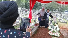 Warga berpose dengan makam Presiden ke-3 RI BJ Habibie dan sang istri, Hasri Ainun Besari di Taman Makam Pahlawan Kalibata, Jakarta, Jumat (13/9/2019). Sehari setelah pemakaman, warga masih berdatangan ke makam Habibie untuk memanjatkan doa dan berfoto. (Liputan6.com/Herman Zakharia)