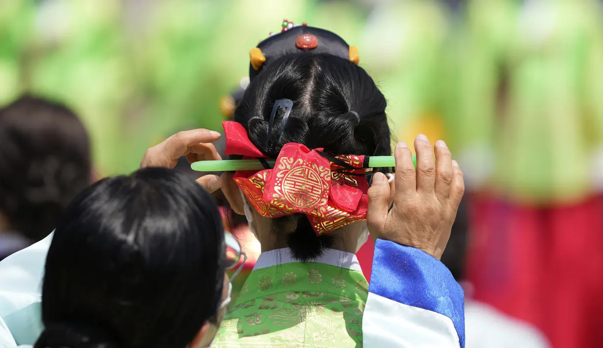 Seorang wanita menata rambut gadis muda saat upacara untuk menghidupkan kembali Hari Kedewasaan ke-50 di Desa Hanok Namsangol di Seoul, Korea Selatan (16/5/2022). Upacara diadakan untuk pria dan wanita muda yang akan berusia 20 tahun. (AP Photo/Lee Jin-man)