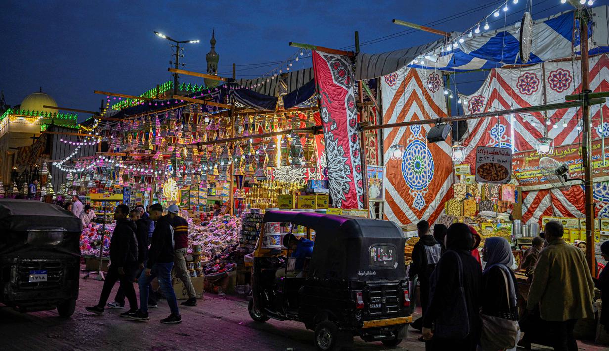 Berasal dari abad ke-10 (era Dinasti Fatimiyah), lentera ini melambangkan cahaya kebaikan, harapan, kegembiraan, dan persatuan. Tampak dalam foto, orang-orang berjalan melewati sebuah toko yang memajang lampion tradisional, barang dekoratif populer yang digunakan selama bulan Ramadan, di sebuah pasar di distrik Sayyida Zeinab di kawasan kota tua Kairo pada Kamis 12 Februari 2026. (Khaled DESOUKI/AFP)