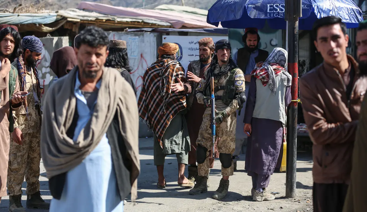 Pria Afghanistan dan personel keamanan Taliban berjaga di sepanjang pinggir jalan setelah baku tembak meletus antara pasukan perbatasan Afghanistan dan Pakistan di dekat perbatasan Torkham yang melintasi antara Afghanistan dan Pakistan, di provinsi Nangarhar pada 20 Februari 2023. Tembakan meletus antara pasukan perbatasan Afghanistan dan Pakistan setelah otoritas Taliban menutup penyeberangan tersibuk negara itu dengan tetangga timurnya, kata para pejabat. (Shafiullah KAKAR / AFP)