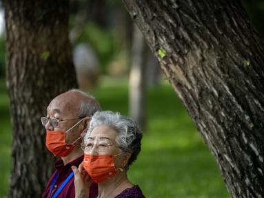 Orang-orang yang memakai masker duduk di bangku di taman umum di Beijing, Jumat (8/7/2022). Ibu kota China, Beijing, tampaknya telah membatalkan rencana untuk mengeluarkan mandat yang mengharuskan orang menunjukkan bukti vaksinasi COVID-19 untuk masuk ke ruang publik tertentu setelah penolakan di kalangan penduduk. (AP Photo/Mark Schiefelbein)
