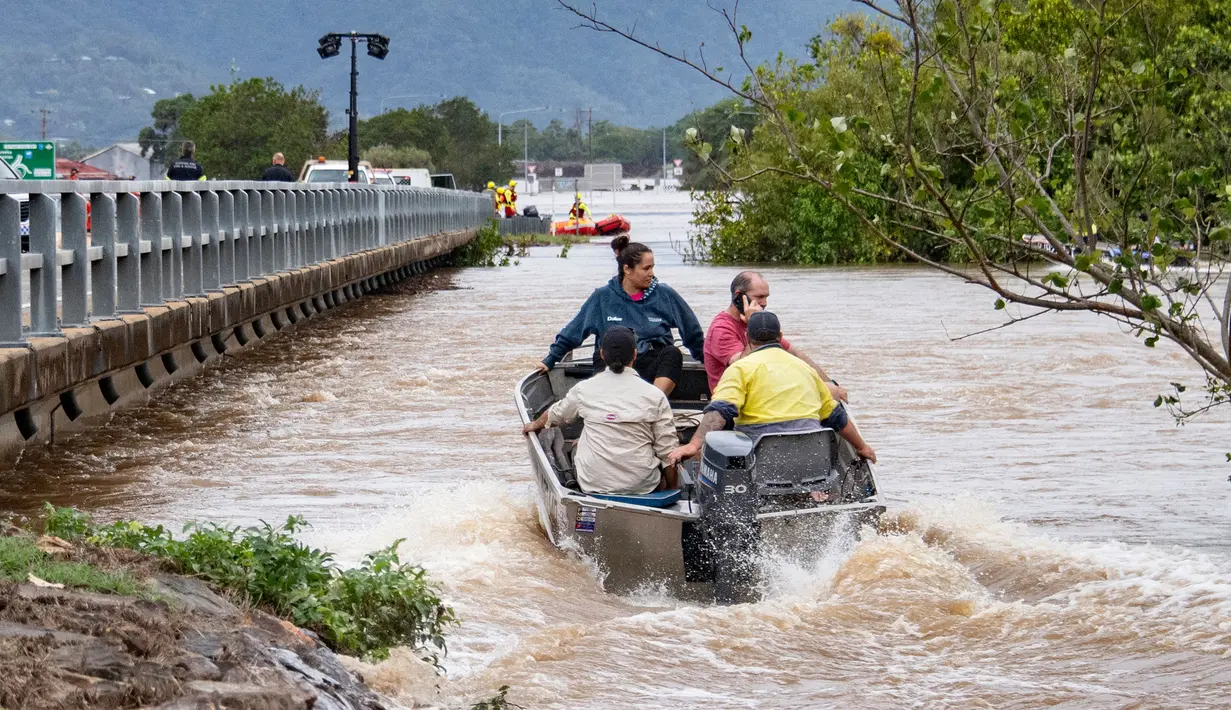 Warga menyeberangi banjir dengan perahu di Cairns pada 18 Desember 2023. (Brian CASSEY/AFP)