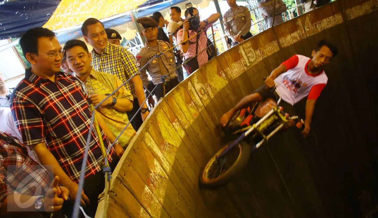 Cagub DKI Jakarta, Basuki T Purnama menyaksikan atraksi Tong Setan saat acara "Bersyukur Jakarta", Jumat (20/1). Dalam acara yang berbentuk bakti sosial dan pasar murah tersebut, terdapat hiburan dan permainan anak. (Liputan6.com/Immanuel Antonius)