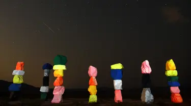 Meteor Perseid melintasi langit di atas instalasi seni "Seven Magic Mountains" dekat Jean, Nevada (13/8). Puncak hujan meteor perseid terjadi pada 11-12 Agustus dan 12-13 Agustus. (AFP Photo/Ethan Miller)