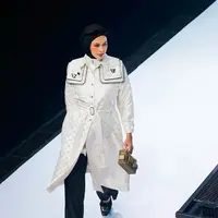 Paula mengenakan trench coat putih dengan monogram khas Vivi Zubedi yang dipadukan dengan celana hitam panjang.  [@vivizubedi].