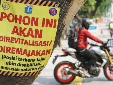 Poster revitalisasi menempel pada pohon yang berada di jalur pedestrian Jalan Kramat Raya, Jakarta, Jumat (8/11/2019). Sepanjang pengerjaan jalur pedestrian, pohon yang berada di jalur tersebut rencananya juga akan direvitalisasi dan diremajakan. (Liputan6.com/Immanuel Antonius)