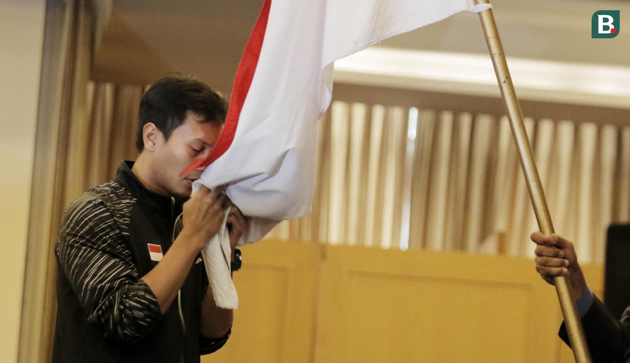Atlet Bulutangkis Indonesia, Mohammad Ahsan, mencium bendera saat acara pelepasan di Hotel Atlet Century, Senayan, Selasa (8/5/2018). Acara pelepasan tersebut sekaligus merayakan ulang tahun PBSI ke 67. (Bola.com/M Iqbal Ichsan)