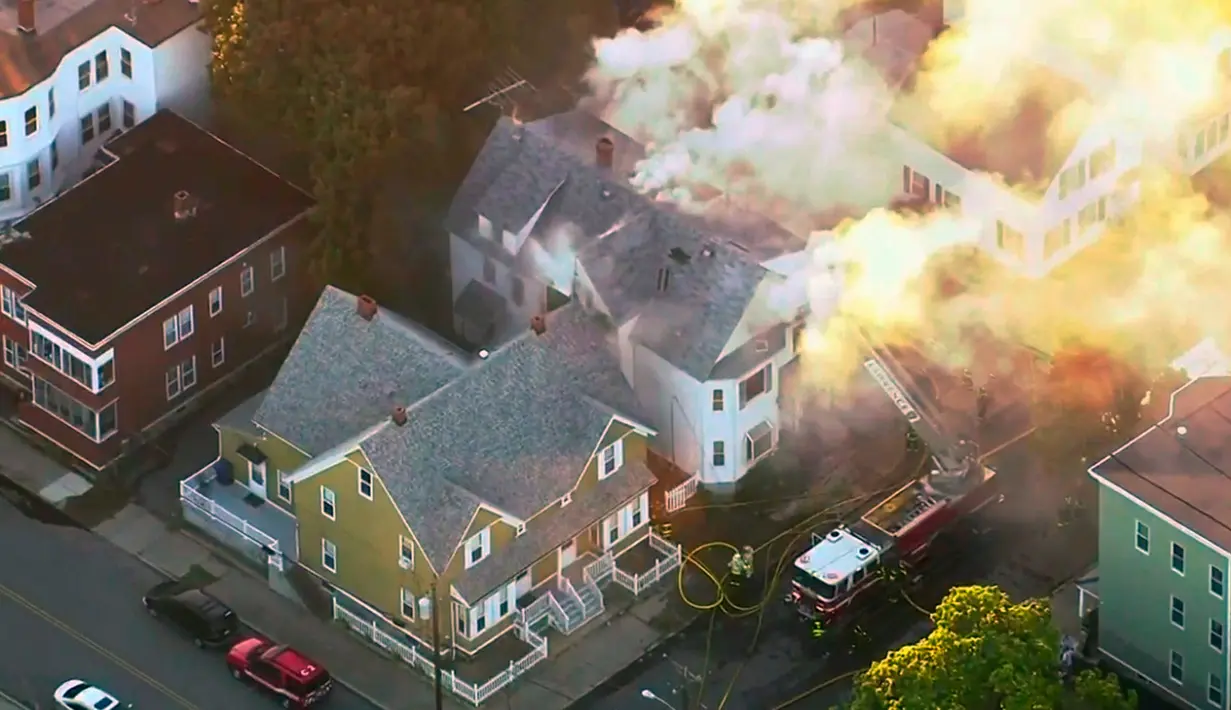 Petugas pemadam kebakaran berusaha menjinakkan api yang melalap rumah di Lawrance, dekat Boston, AS, Kamis (13/9). Rentetan ledakan dan kebakaran di tiga komunitas utara Boston itu membuat pihak berwenang memutus aliran listrik dan gas. (WCVB via AP)