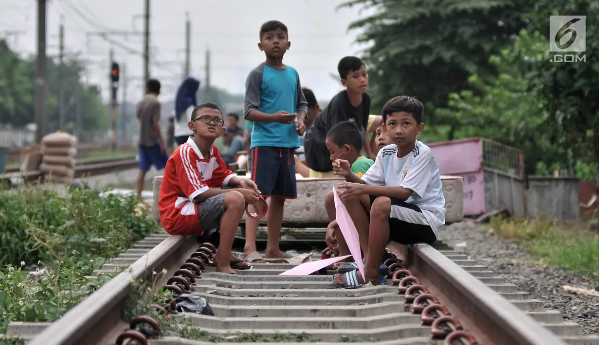Anak-anak membawa layang-layang di rel kereta api kawasan Jakarta Timur, Kamis (3/1). Minimnya lahan terbuka hijau memaksa anak-anak setempat memilih kawasan rel kereta api sebagai lokasi bermain. (Merdeka.com/Iqbal Nugroho)